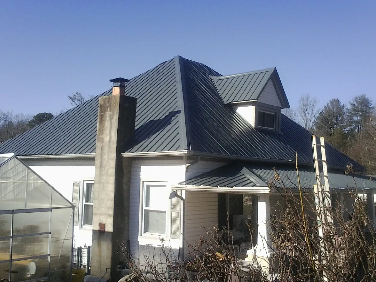 Dark blue standing seam metal roof on a white farmhouse with dormer — Slate & Tile Roof Repair by Roofing Brothers in Red Wing