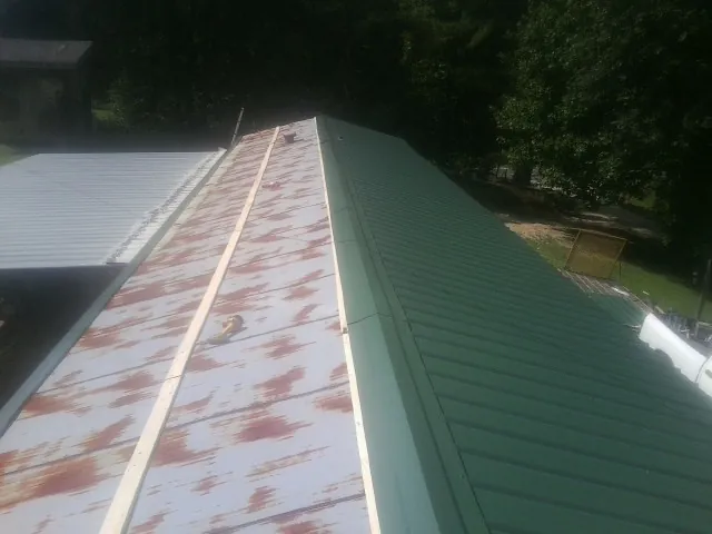 Old rusted panels beside newly installed green metal roofing — Wind Damage Roof Repair by Roofing Brothers in Red Wing