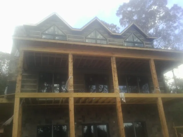 Dormers and porch framing on a large log home under construction — Roof Coating work by our crew in Red Wing