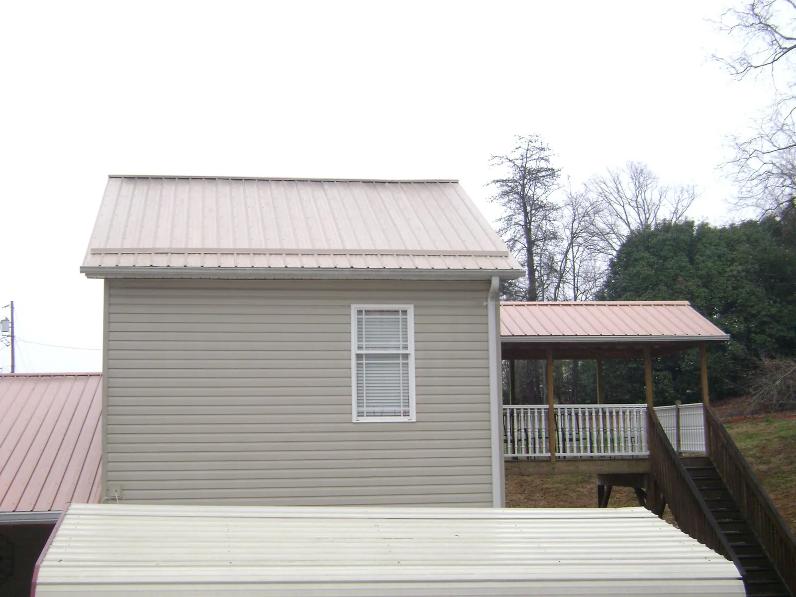 Tan metal roofs on a two story addition and attached porch, from a Roof Replacement job in Red Wing