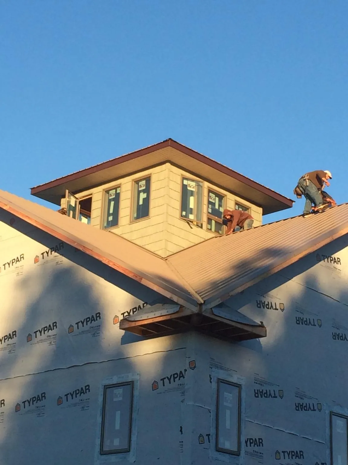 Roofers working around a rooftop cupola on a new metal roof at sunset — Roof Waterproofing in Red Wing by Roofing Brothers